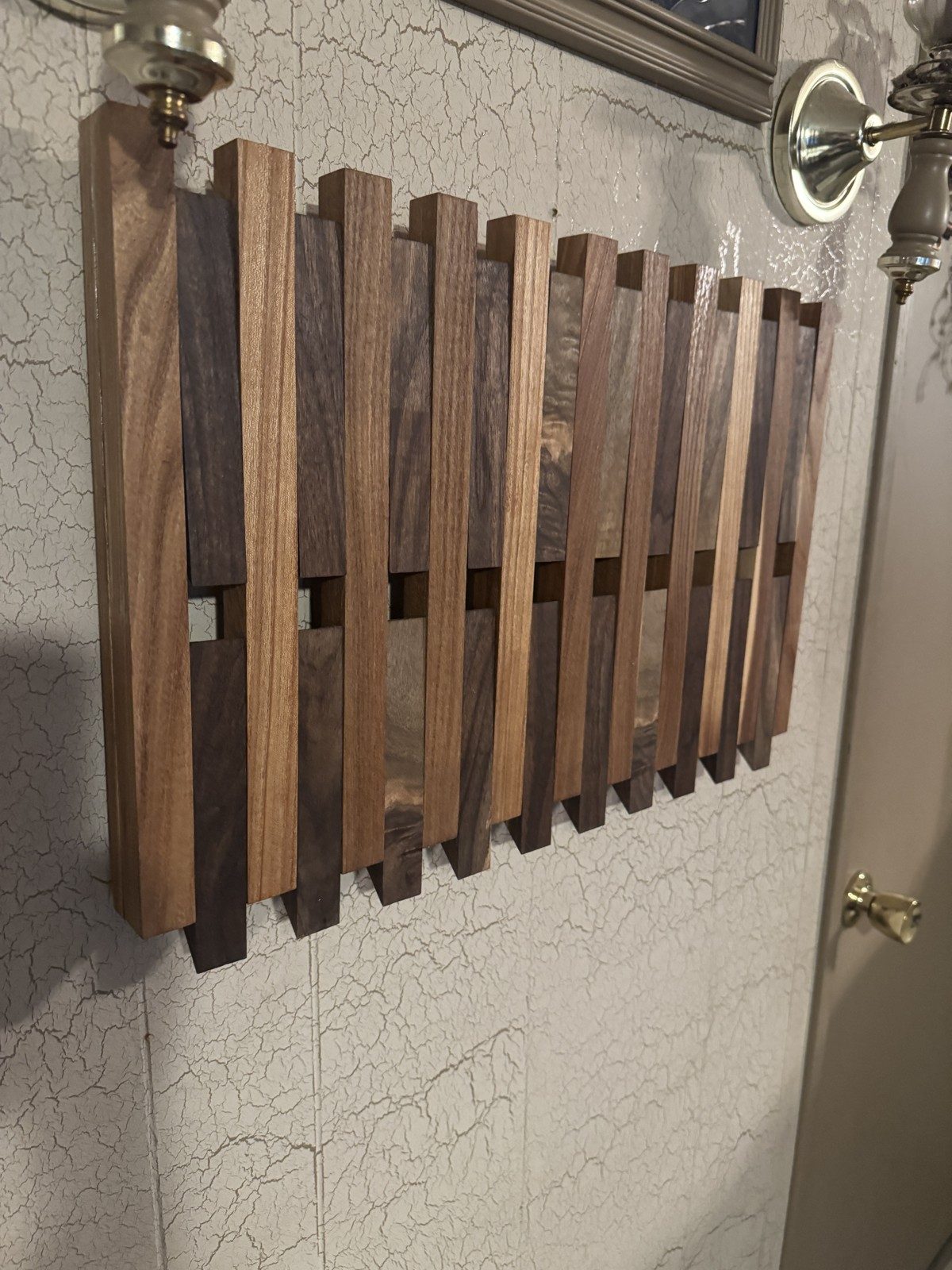 The Walnut & Elm Key Rack hung on a wall, seen from a side angle with the hooks folded up